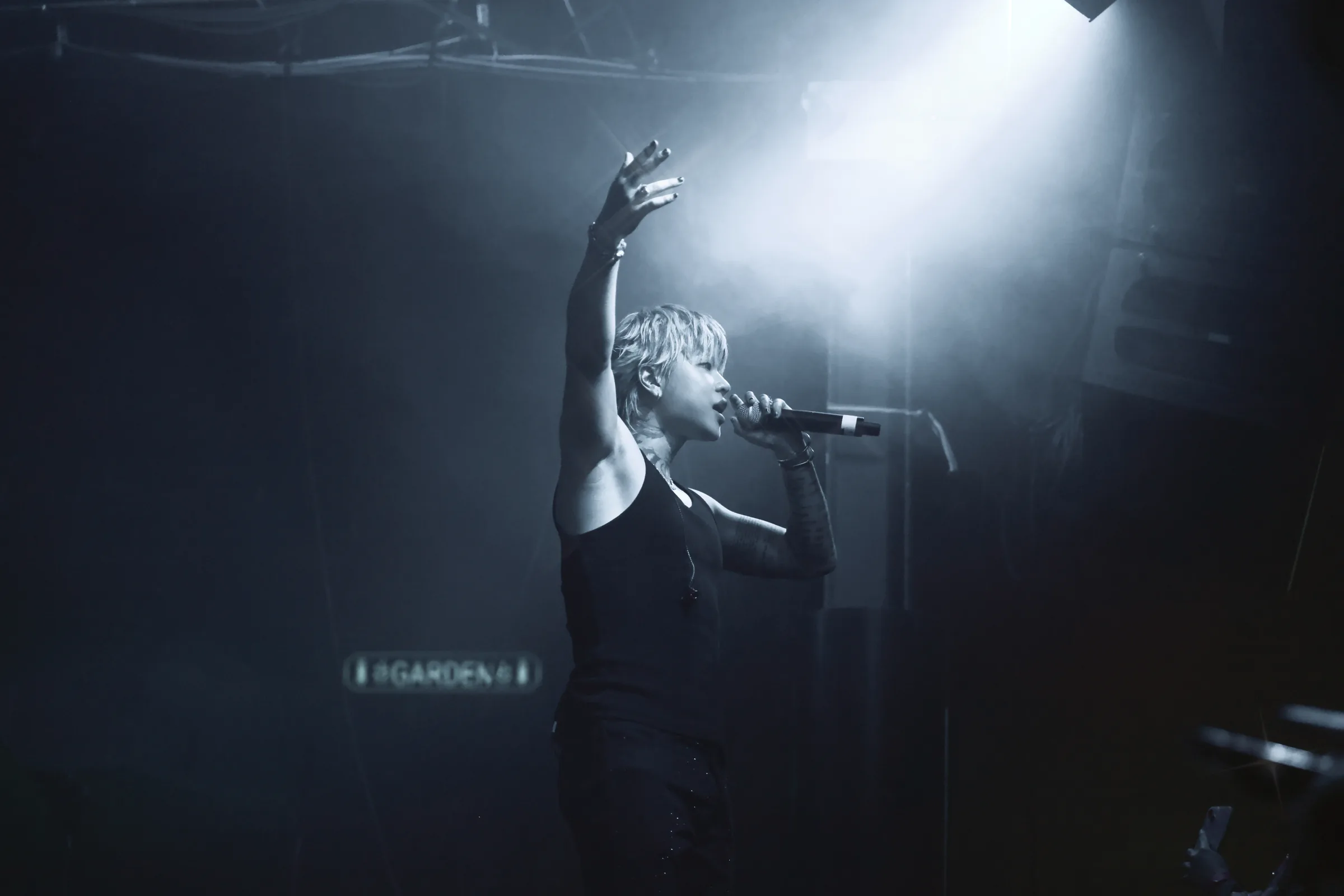 ASH ISLAND raising a hand in silhouette under blue-white stage light