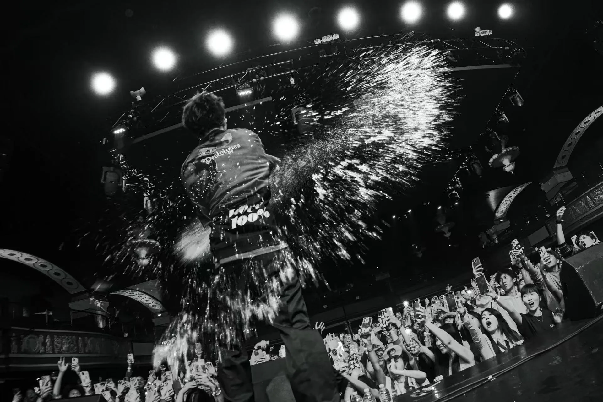 TizzyT performing before the crowd beneath an overhead water effect